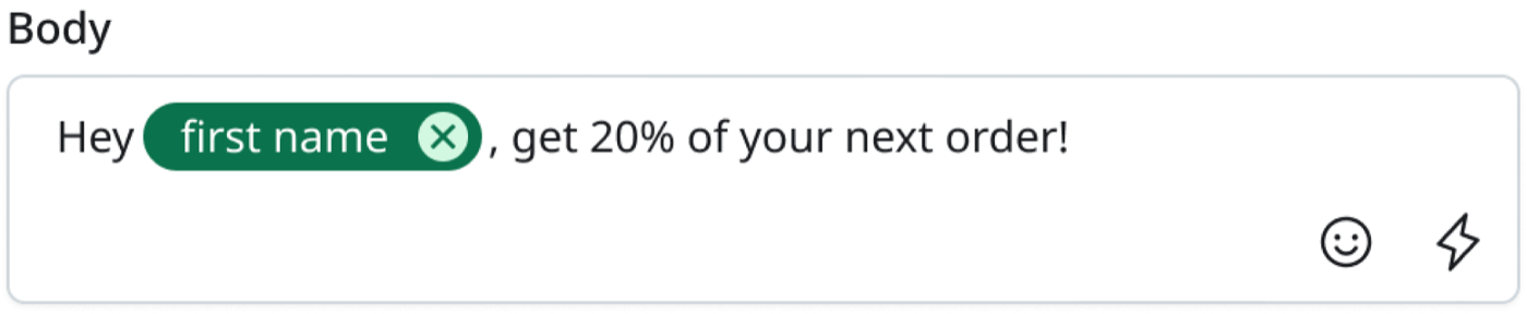 A message Body field containing the text 'Hey', then a green rounded token labelled 'first name' with a small remove button, then ', get 20% of your next order!'. An emoji button and a personalisation button sit at the bottom right of the field.